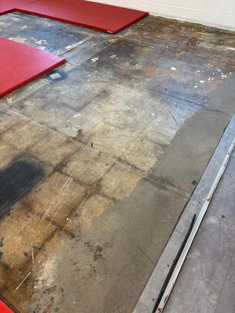 Bare worn floor area next to red training mats in a gym